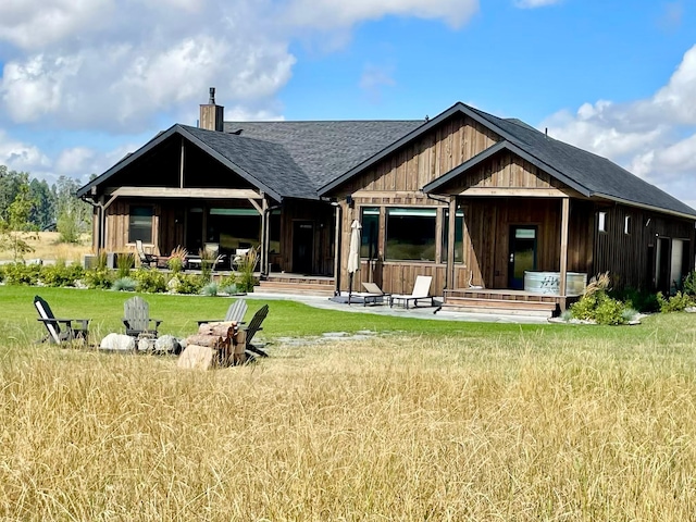 27 Elk Meadow Ln, Kalispell, MT 59901 - rear view of house featuring a chimney, a yard, a shingled roof, and board and batten siding