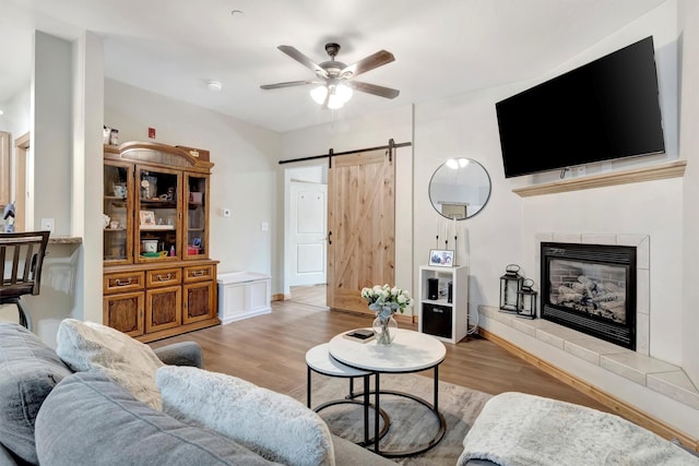 4100 Mullan Rd Unit 102, Missoula, MT 59808 - living room featuring a barn door, a ceiling fan, wood finished floors, and a tiled fireplace