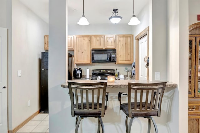 4100 Mullan Rd Unit 102, Missoula, MT 59808 - kitchen with black appliances, light brown cabinetry, a breakfast bar area, light tile patterned floors, and hanging light fixtures
