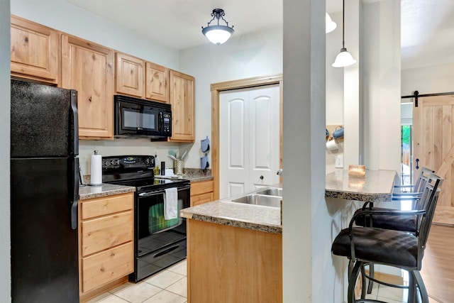 4100 Mullan Rd Unit 102, Missoula, MT 59808 - kitchen with black appliances, light brown cabinetry, a barn door, a kitchen breakfast bar, and light tile patterned floors