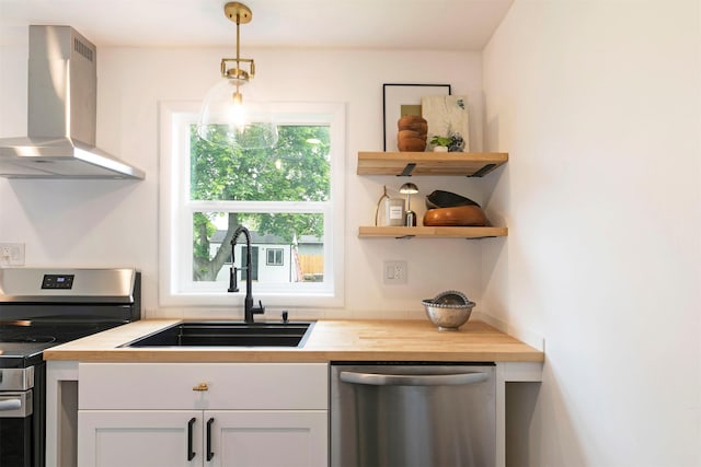 2929 Sunrise Promenade Promenade, Missoula, MT 59801 - kitchen featuring stainless steel appliances, wall chimney exhaust hood, a sink, white cabinets, and wooden counters