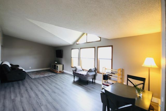 4757 Richlie, Missoula, MT 59808 - living area featuring wood finished floors, baseboards, vaulted ceiling, and a textured ceiling