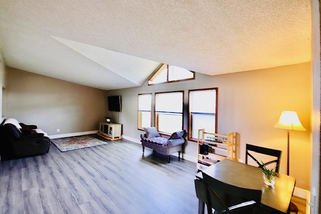 4757 Richlie, Missoula, MT 59808 - living room featuring wood finished floors, a textured ceiling, baseboards, and lofted ceiling