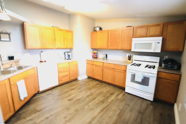 4757 Richlie, Missoula, MT 59808 - kitchen featuring white appliances, a sink, light wood finished floors, light countertops, and light brown cabinets