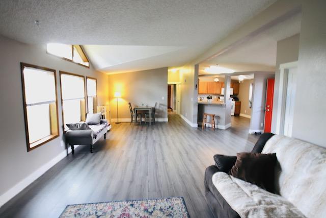 4757 Richlie, Missoula, MT 59808 - living area with wood finished floors, baseboards, vaulted ceiling, and a textured ceiling