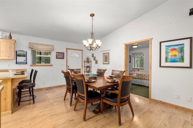 13033 Trinkus Ln, Bigfork, MT 59911 - dining space featuring lofted ceiling, a chandelier, light wood-style floors, and baseboards