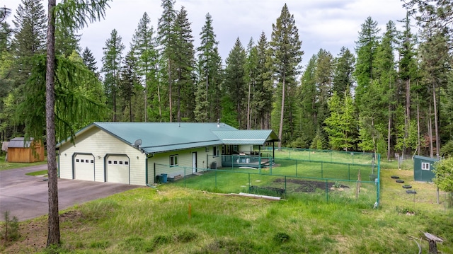 13033 Trinkus Ln, Bigfork, MT 59911 - view of front of home with an attached garage, driveway, a wooded view, and metal roof