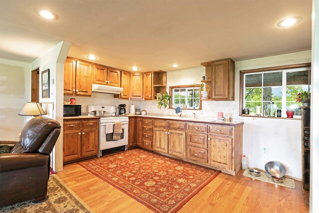 874 Coal Pit Rd, Corvallis, MT 59828 - kitchen with white range with gas cooktop, black microwave, under cabinet range hood, open shelves, and light wood-type flooring