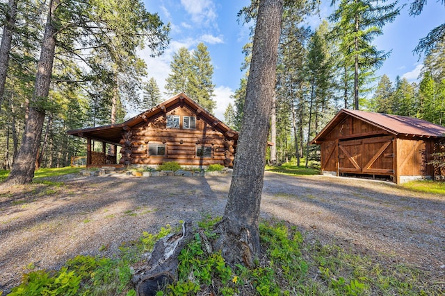 131 Mccaffery Lookout Trl, Bigfork, MT 59911 - view of front of house featuring log siding, an outdoor structure, and gravel driveway