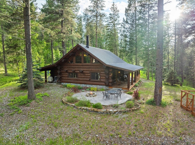 131 Mccaffery Lookout Trl, Bigfork, MT 59911 - back of house with a fire pit, log siding, metal roof, a patio area, and a view of trees