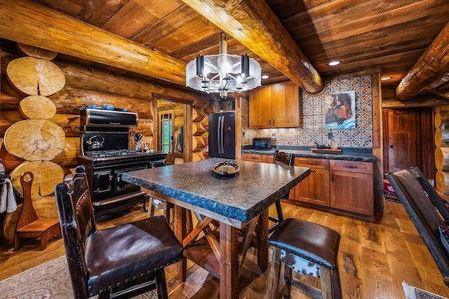 131 Mccaffery Lookout Trl, Bigfork, MT 59911 - kitchen with freestanding refrigerator, wooden ceiling with exposed beams, dark countertops, light wood finished floors, and rustic walls