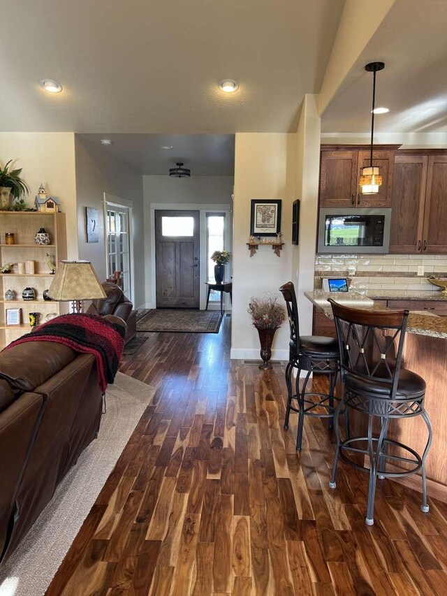 2669 Bunkhouse Pl, Missoula, MT 59808 - kitchen featuring black microwave, open floor plan, dark wood-style flooring, decorative backsplash, and baseboards