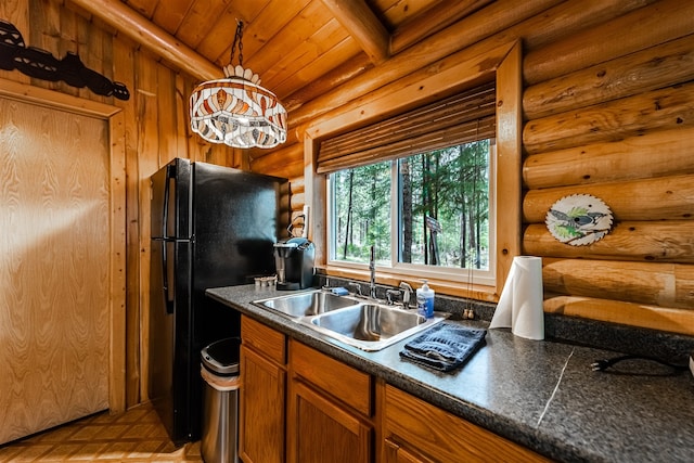 204 Cougar Meadow Dr, Saint Regis, MT 59866 - kitchen featuring a sink, rustic walls, freestanding refrigerator, wood ceiling with exposed beams, and brown cabinetry