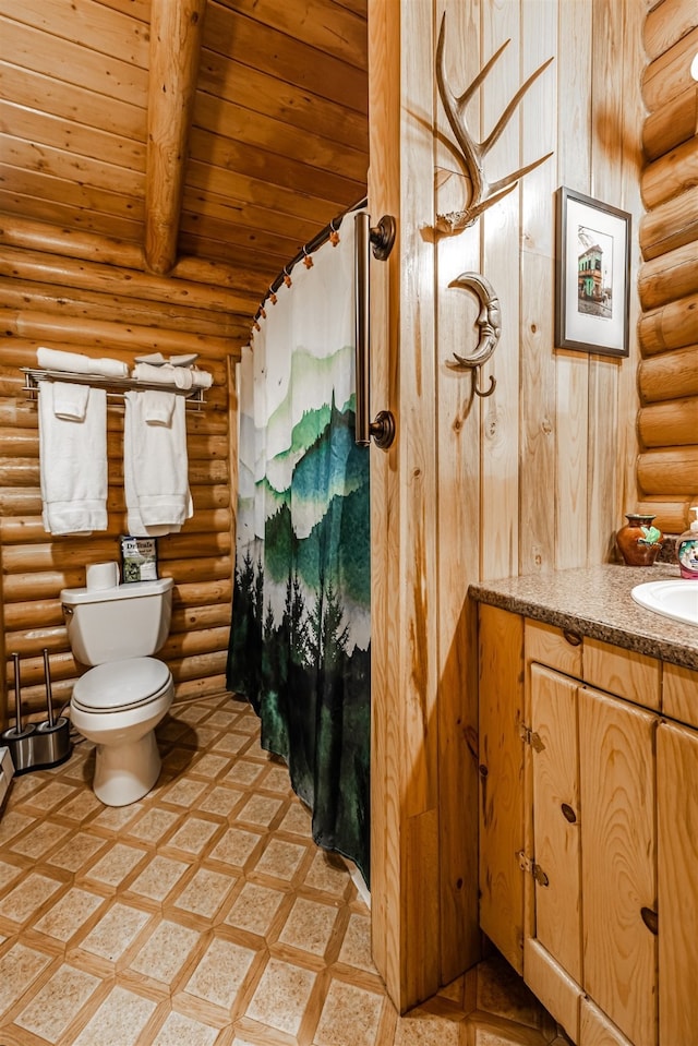 204 Cougar Meadow Dr, Saint Regis, MT 59866 - full bath featuring log walls, toilet, wooden ceiling with exposed beams, vanity, and a shower with shower curtain