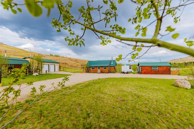 34 Outlaw Trl, Anaconda, MT 59711 - view of green lawn featuring driveway, a garage, and an outdoor structure