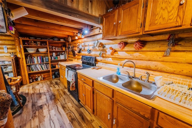 34 Outlaw Trl, Anaconda, MT 59711 - kitchen featuring black electric range oven, rustic walls, a sink, light countertops, and brown cabinetry