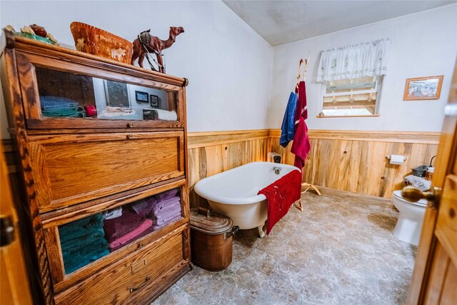 34 Outlaw Trl, Anaconda, MT 59711 - full bathroom with a freestanding bath, a wainscoted wall, toilet, stone finish floors, and wood walls
