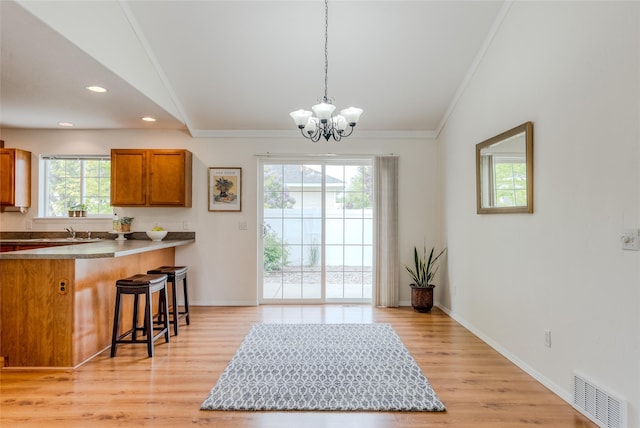 115 River Glen Ct, Kalispell, MT 59901 - kitchen with brown cabinetry, a chandelier, a kitchen breakfast bar, ornamental molding, and decorative light fixtures