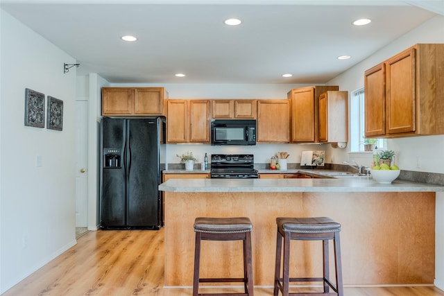 115 River Glen Ct, Kalispell, MT 59901 - kitchen featuring black appliances, a sink, a peninsula, light wood-style floors, and a kitchen bar