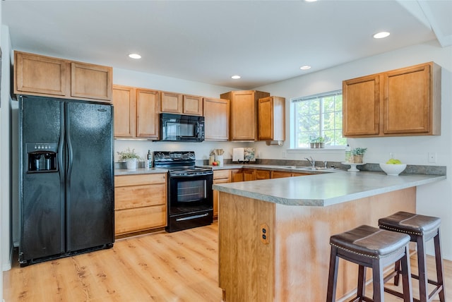 115 River Glen Ct, Kalispell, MT 59901 - kitchen featuring black appliances, a peninsula, a sink, light wood-style floors, and a kitchen breakfast bar