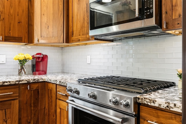 11515 Ninebark Way, Missoula, MT 59802 - kitchen with stainless steel appliances, decorative backsplash, brown cabinetry, and light stone countertops