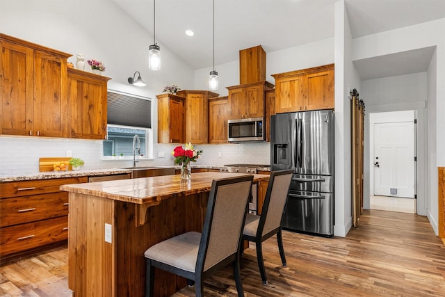 11515 Ninebark Way, Missoula, MT 59802 - kitchen featuring stainless steel appliances, brown cabinets, a kitchen island, wood finished floors, and decorative backsplash