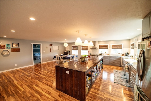 1610 Maple Dr, Fort Benton, MT 59442 - kitchen with appliances with stainless steel finishes, wood counters, light wood-style flooring, wall chimney exhaust hood, and recessed lighting