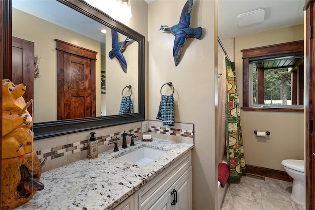 46274 Meadowlark Ln, Big Arm, MT 59910 - full bathroom with tasteful backsplash, vanity, toilet, and baseboards
