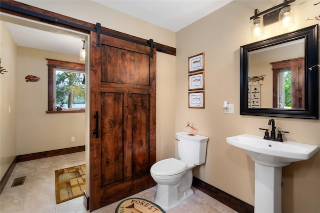 46274 Meadowlark Ln, Big Arm, MT 59910 - bathroom featuring toilet, baseboards, plenty of natural light, and a sink