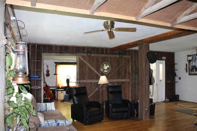 34575 Gunlock Rd, Charlo, MT 59824 - living room featuring a ceiling fan, wood finished floors, beamed ceiling, wooden walls, and healthy amount of natural light