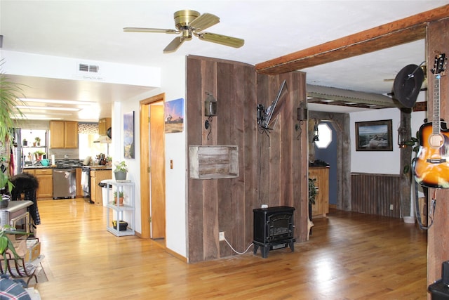 34575 Gunlock Rd, Charlo, MT 59824 - living area with a wood stove, light wood finished floors, a ceiling fan, healthy amount of natural light, and beamed ceiling