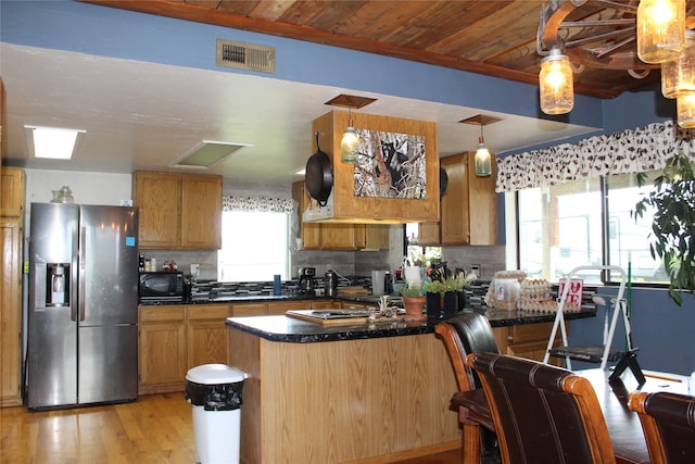 34575 Gunlock Rd, Charlo, MT 59824 - kitchen featuring stainless steel refrigerator with ice dispenser, black microwave, dark countertops, light wood finished floors, and backsplash