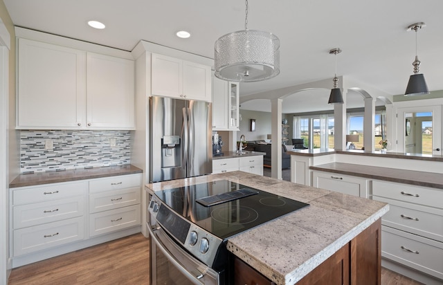 1221 Majestic View Ln, Kalispell, MT 59901 - kitchen featuring stainless steel appliances, decorative columns, arched walkways, a kitchen island, and tasteful backsplash