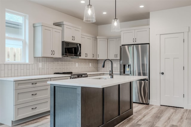 1050 Mill Creek Dr, Bigfork, MT 59911 - kitchen with stainless steel appliances, a sink, backsplash, pendant lighting, and light wood-style flooring