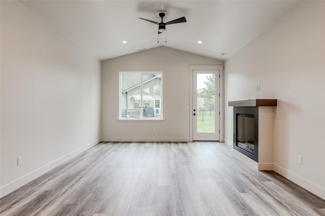 1050 Mill Creek Dr, Bigfork, MT 59911 - unfurnished living room featuring wood finished floors, a ceiling fan, a glass covered fireplace, vaulted ceiling, and baseboards