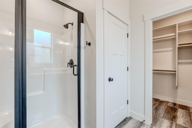 1050 Mill Creek Dr, Bigfork, MT 59911 - full bathroom featuring a shower stall, a walk in closet, baseboards, and wood finished floors