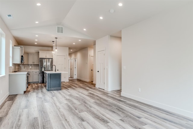 1050 Mill Creek Dr, Bigfork, MT 59911 - kitchen with stainless steel refrigerator with ice dispenser, light countertops, light wood finished floors, a kitchen island with sink, and gray cabinets