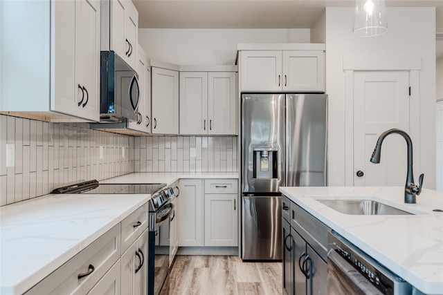 1050 Mill Creek Dr, Bigfork, MT 59911 - kitchen featuring stainless steel appliances, a sink, light stone counters, decorative backsplash, and pendant lighting