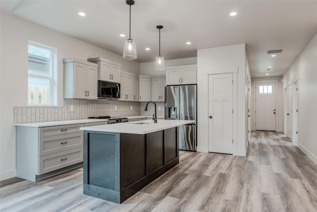 1050 Mill Creek Dr, Bigfork, MT 59911 - kitchen with appliances with stainless steel finishes, a sink, light countertops, tasteful backsplash, and light wood finished floors