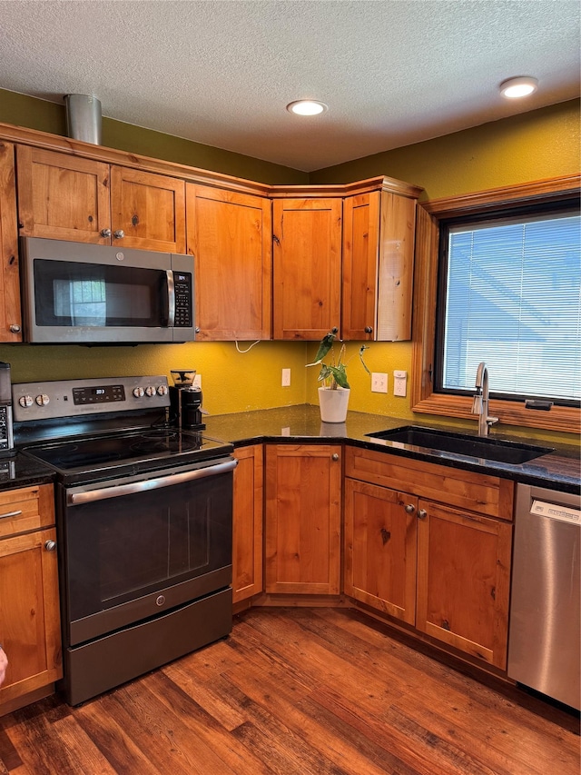 3115 8th Ave N, Great Falls, MT 59401 - kitchen with appliances with stainless steel finishes, dark wood-type flooring, a textured ceiling, brown cabinetry, and recessed lighting