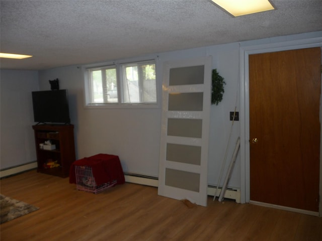3115 8th Ave N, Great Falls, MT 59401 - basement featuring a baseboard heating unit, a textured ceiling, a baseboard radiator, and wood finished floors