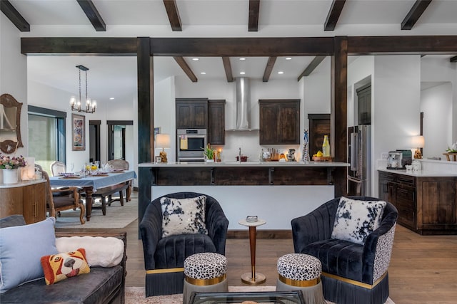 344 Chapman Ln, Bigfork, MT 59911 - kitchen with wall chimney range hood, stainless steel appliances, light countertops, beamed ceiling, and a chandelier