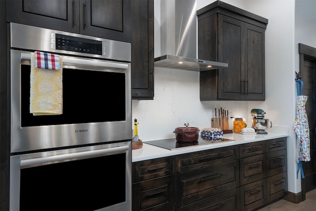 344 Chapman Ln, Bigfork, MT 59911 - kitchen featuring wall chimney exhaust hood, double oven, black electric stovetop, light countertops, and dark brown cabinetry