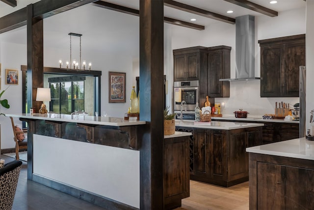 344 Chapman Ln, Bigfork, MT 59911 - kitchen featuring wall chimney exhaust hood, oven, beamed ceiling, light countertops, and dark brown cabinets