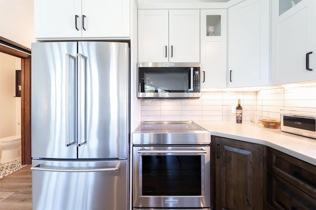 550 Talbot Rd, Columbia Falls, MT 59912 - kitchen with appliances with stainless steel finishes, light countertops, glass insert cabinets, white cabinetry, and wood finished floors