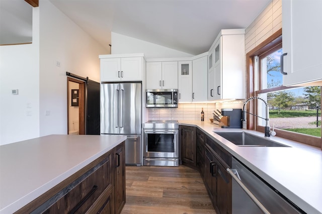 550 Talbot Rd, Columbia Falls, MT 59912 - kitchen featuring stainless steel appliances, a sink, vaulted ceiling, decorative backsplash, and white cabinets