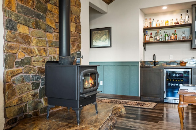 17 River Runs Ct, Plains, MT 59859 - indoor wet bar featuring beverage cooler, a wood stove, wainscoting, dark wood-type flooring, and a decorative wall