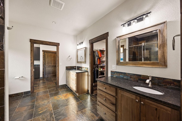 17 River Runs Ct, Plains, MT 59859 - full bath with stone tile flooring, a walk in closet, two vanities, and a stall shower