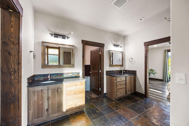 17 River Runs Ct, Plains, MT 59859 - full bath with two vanities, stone finish flooring, and a textured ceiling