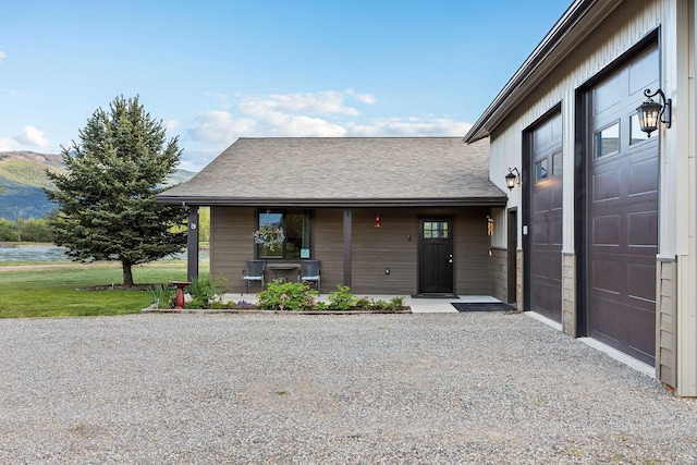 17 River Runs Ct, Plains, MT 59859 - doorway to property with covered porch, a garage, a water and mountain view, gravel driveway, and roof with shingles